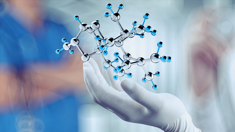 Gloved hand holding molecular structure.
